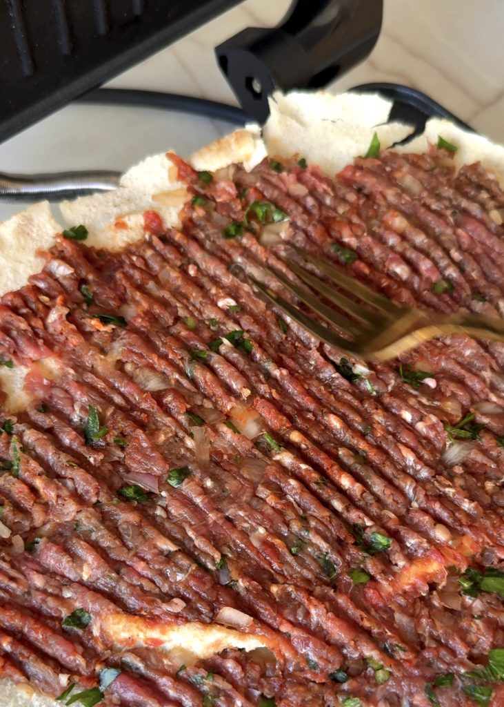 Prepare the Kofta Mix and Flatbread:
Mix ground beef, onion, parsley, salt, pepper, and paprika until combined. Cut the flatbread in half, open it, and spread a thin layer of the beef mixture over one side.