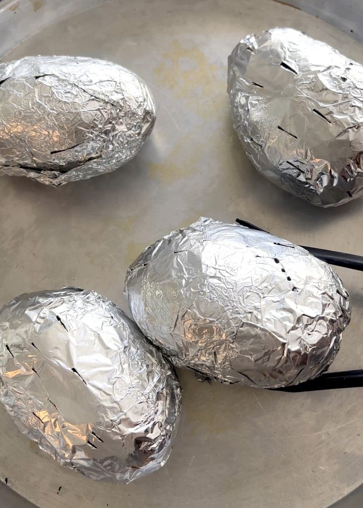 Prepare the Potatoes: Rub them with oil and salt, poke with a fork, and wrap in foil.