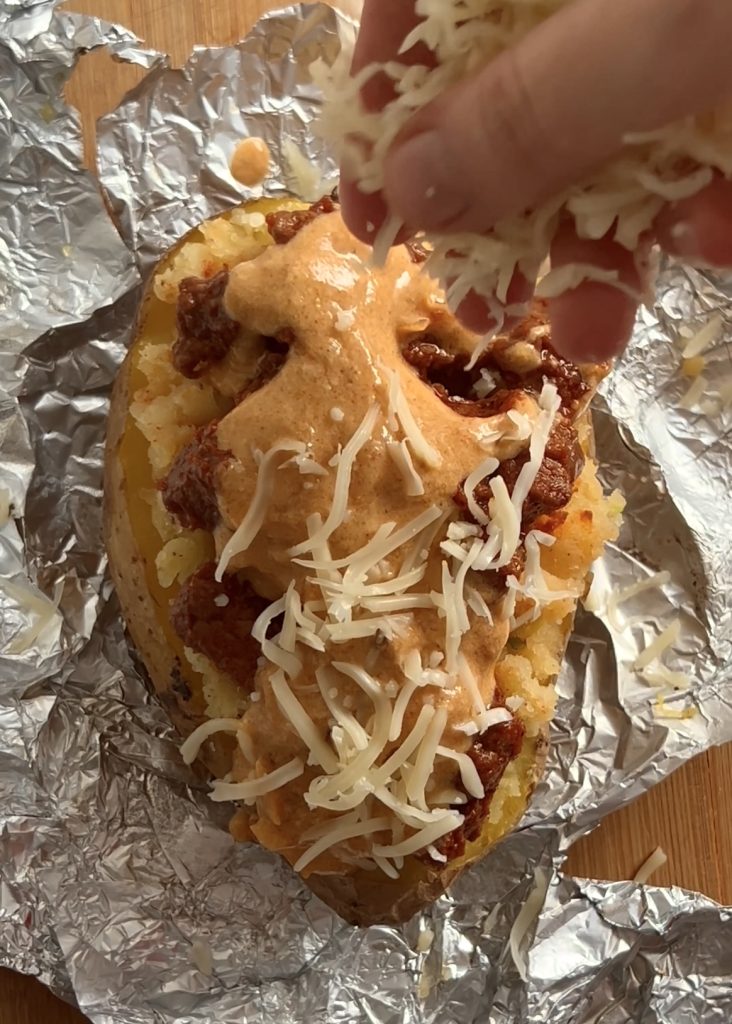 Assemble the Potatoes: Scoop out the flesh, mash it, season, and layer with cheese, beef, and sauce.