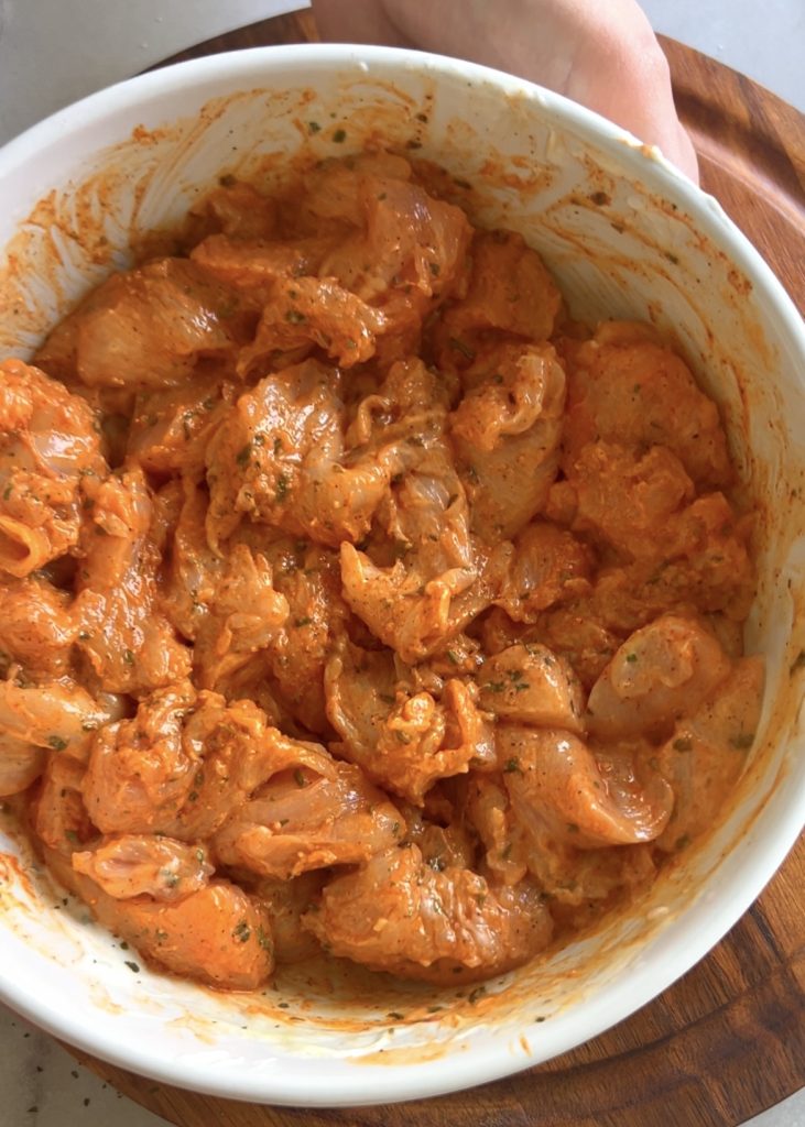 Cut the chicken into cubes and combine with yogurt, oil, spices, lemon, parmesan, and herbs until well coated.