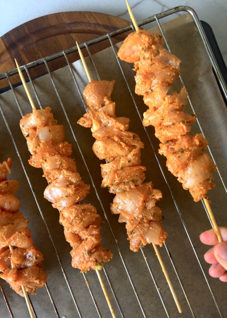 Thread the marinated chicken pieces onto skewers.