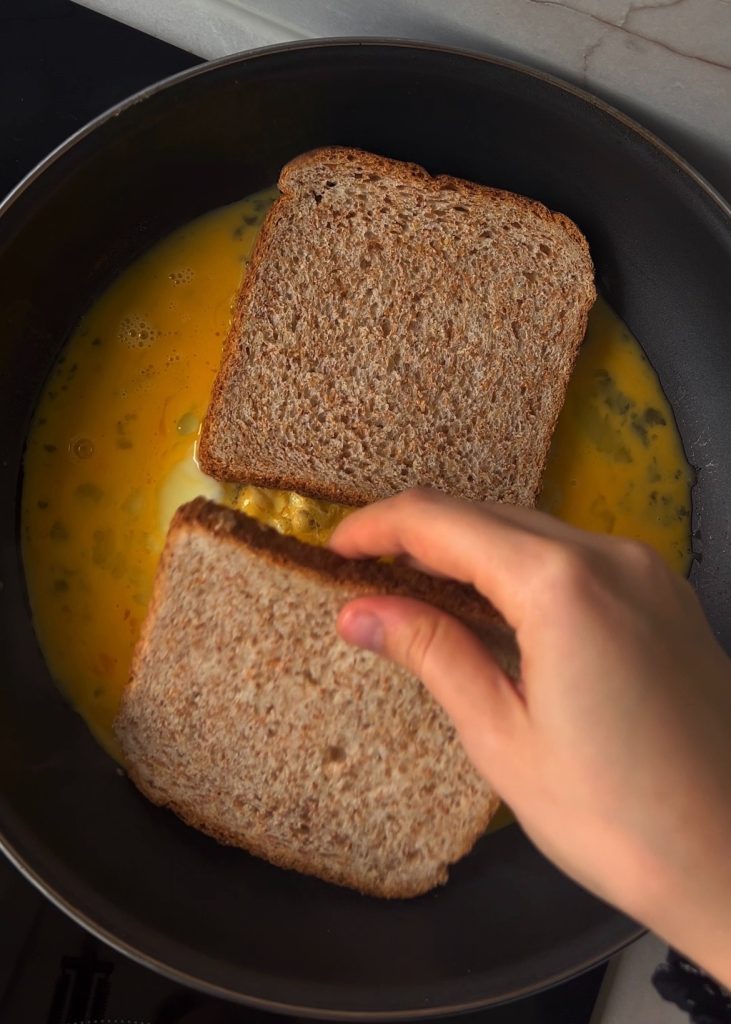 Add toast on top. Place the bread on the eggs, then flip so the eggs sit on top of the toast.
