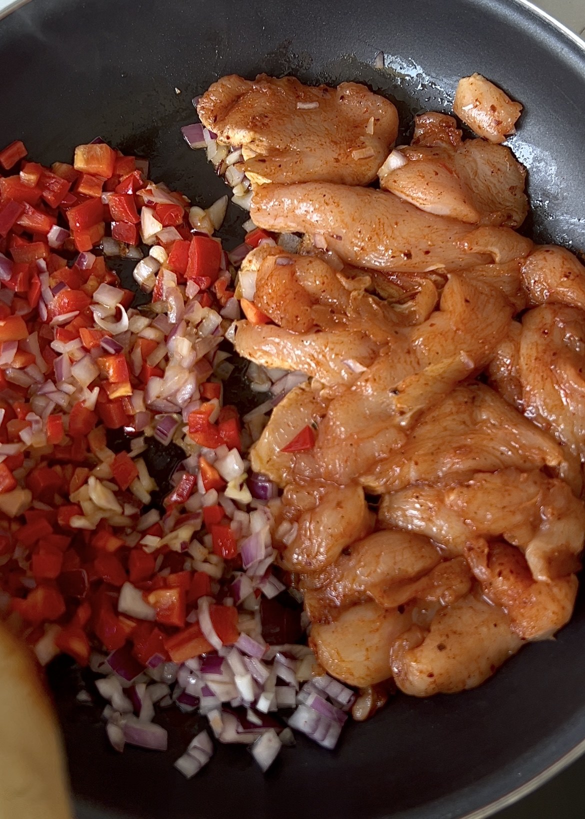 Sliced chicken, pepper and onion in the cooking pan