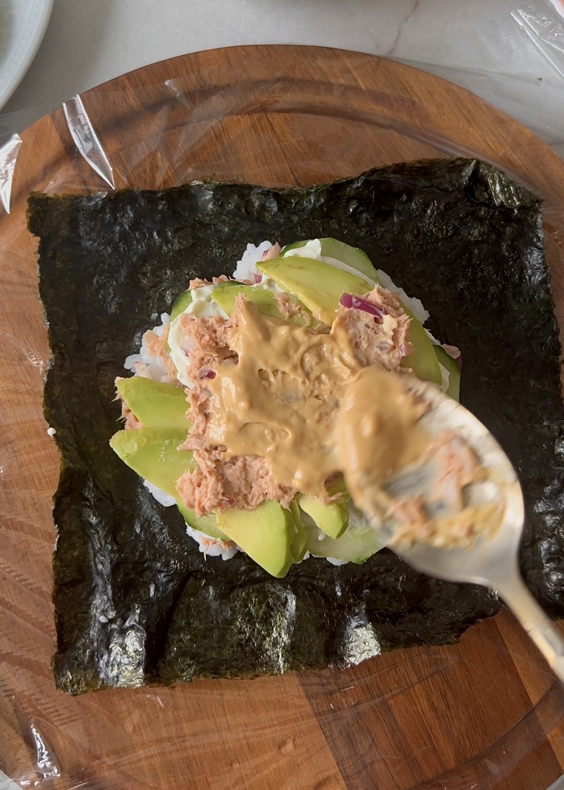 Layering sushi rice, tuna and vegetables on nori