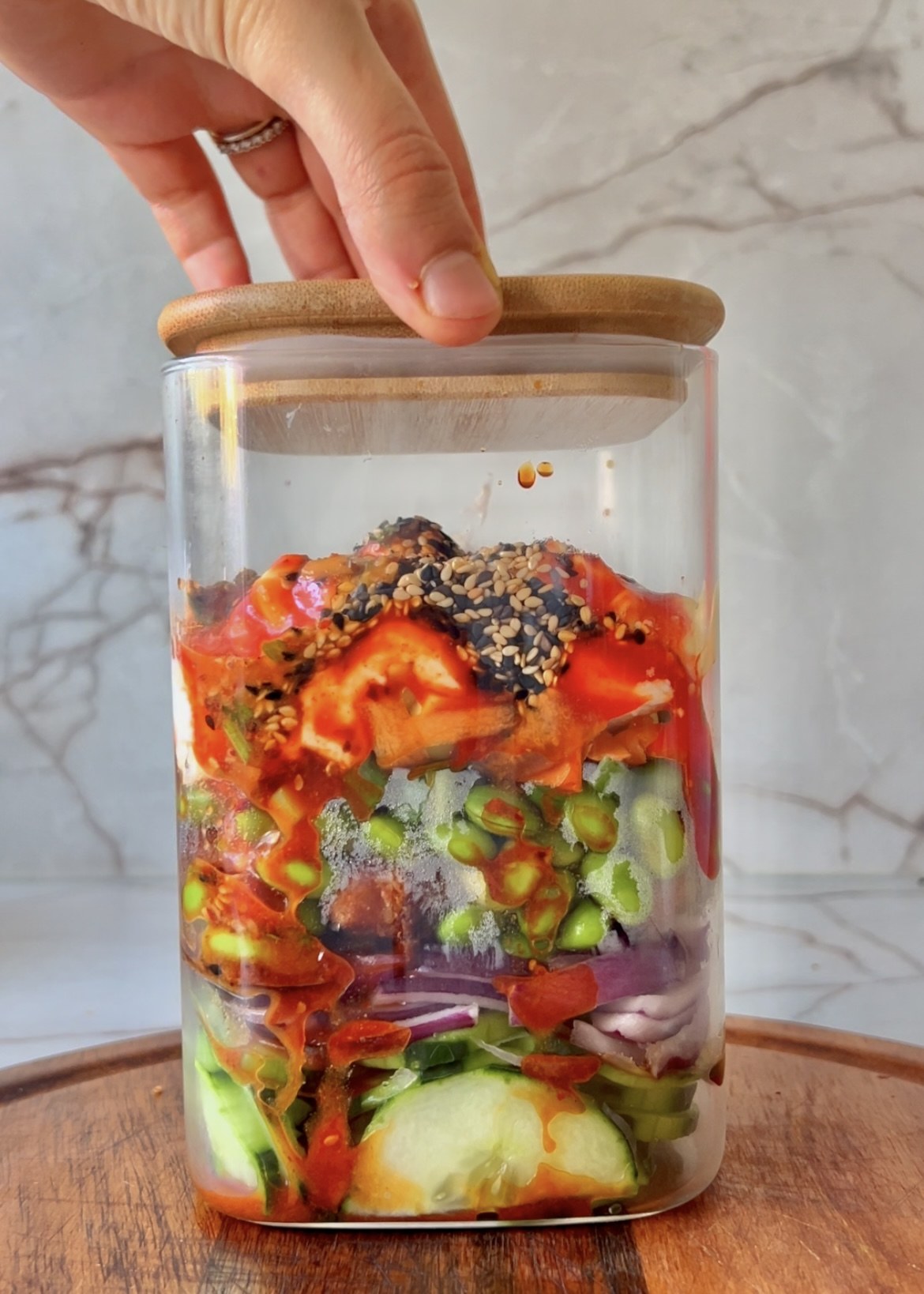 Sliced cucumber and salad ingredients layered in a jar