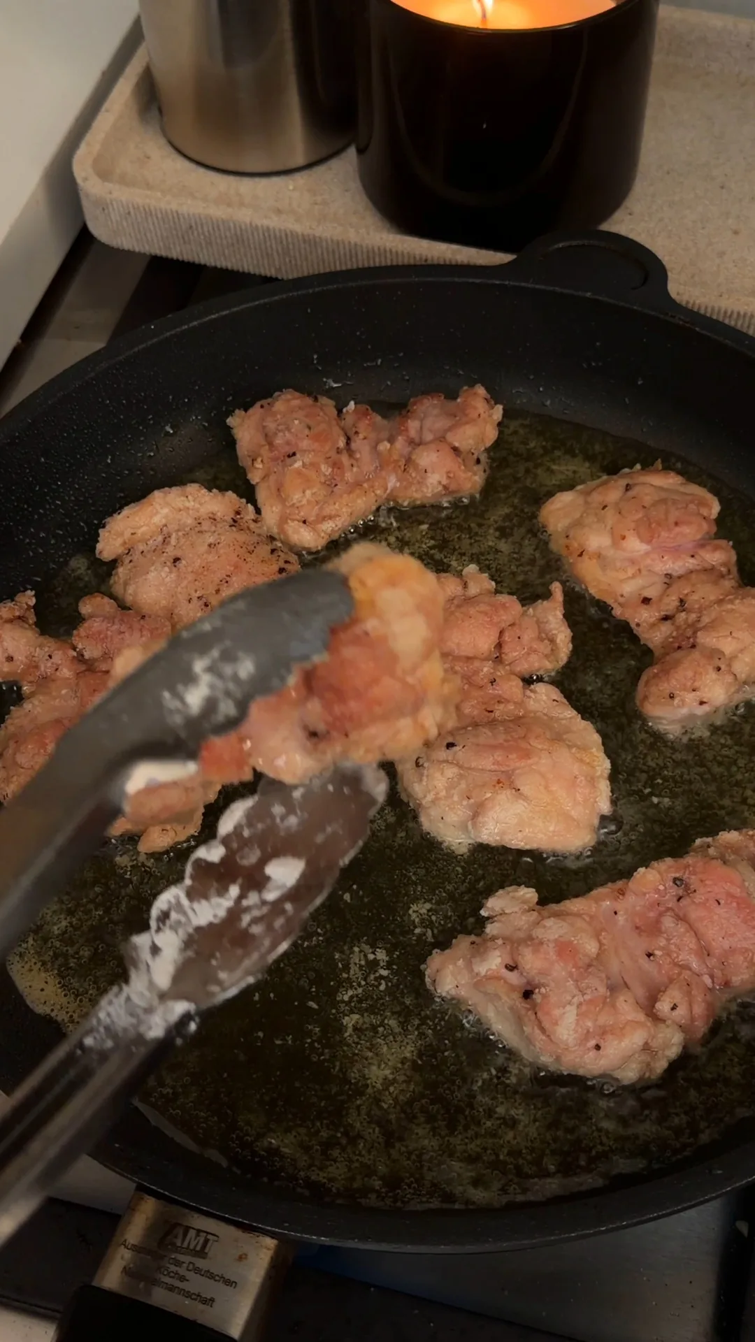 Chicken thighs browning in oil in a frying pan