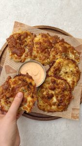 Golden cheesy smashed potatoes on a tray with creamy Sriracha dip