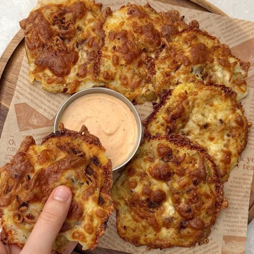 Golden cheesy smashed potatoes on a tray with creamy Sriracha dip