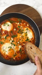 Shakshuka with eggs, feta and parsley served with bread
