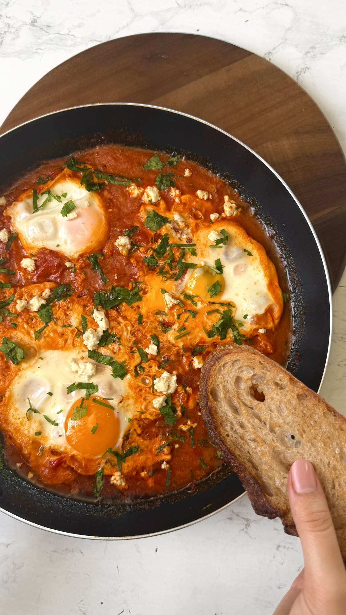 Shakshuka with eggs, feta and parsley served with bread