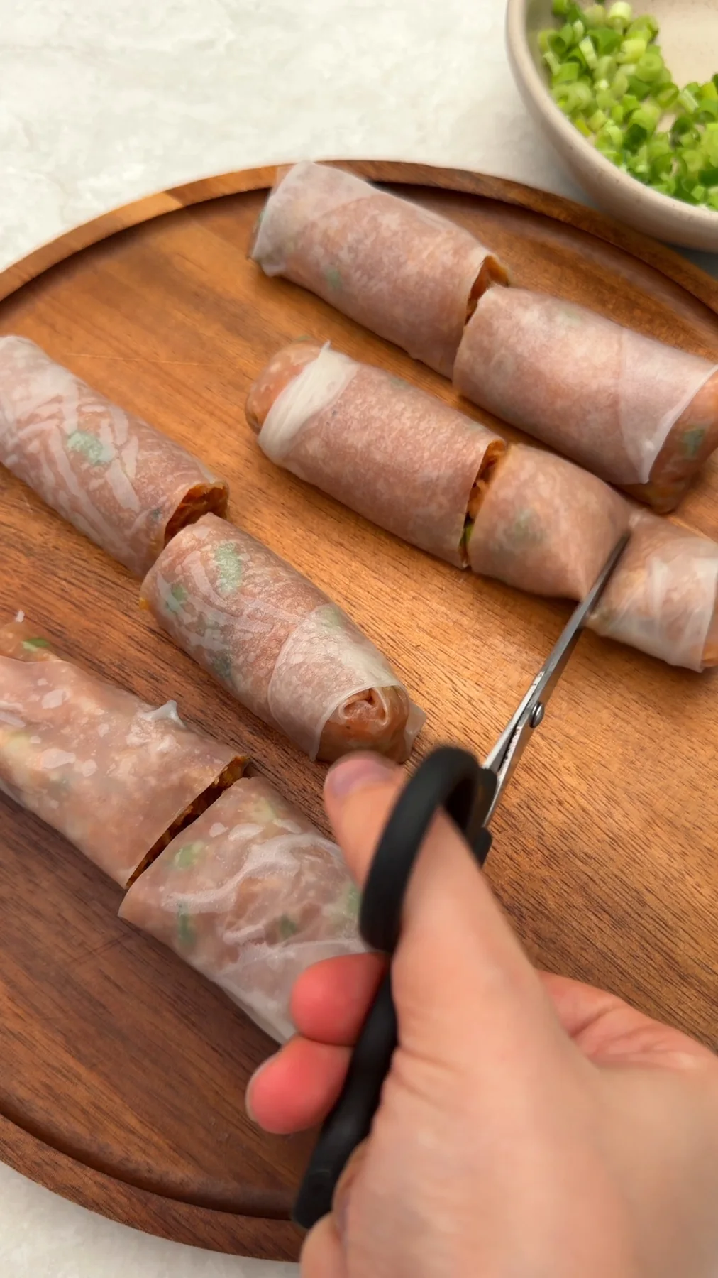 Kitchen scissors cutting chicken rice paper rolls into bites